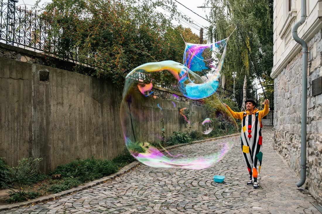 Balon uriaș de săpun pe o stradă pietruită, cu artistul Royal Entertainment