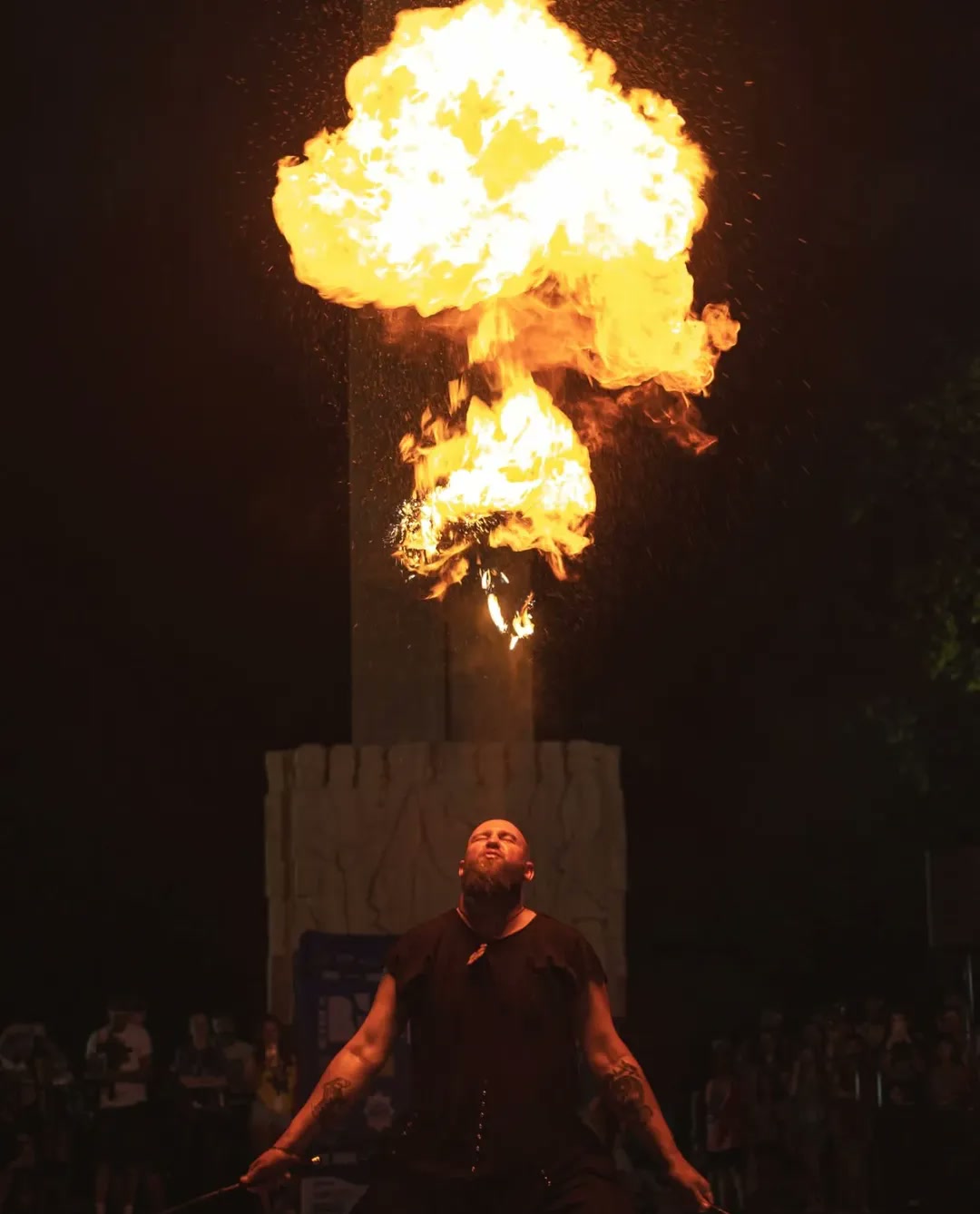 Fire breather sending a column of flame above the crowd
