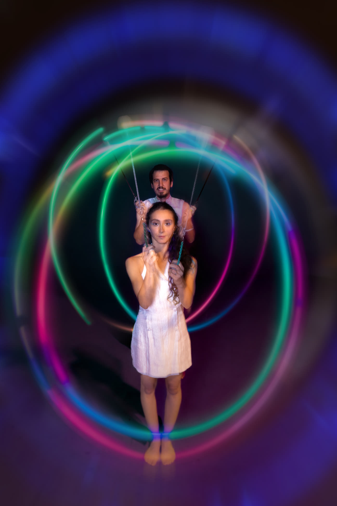 LED juggling duo spinning glowing poi, colour trails around the performers