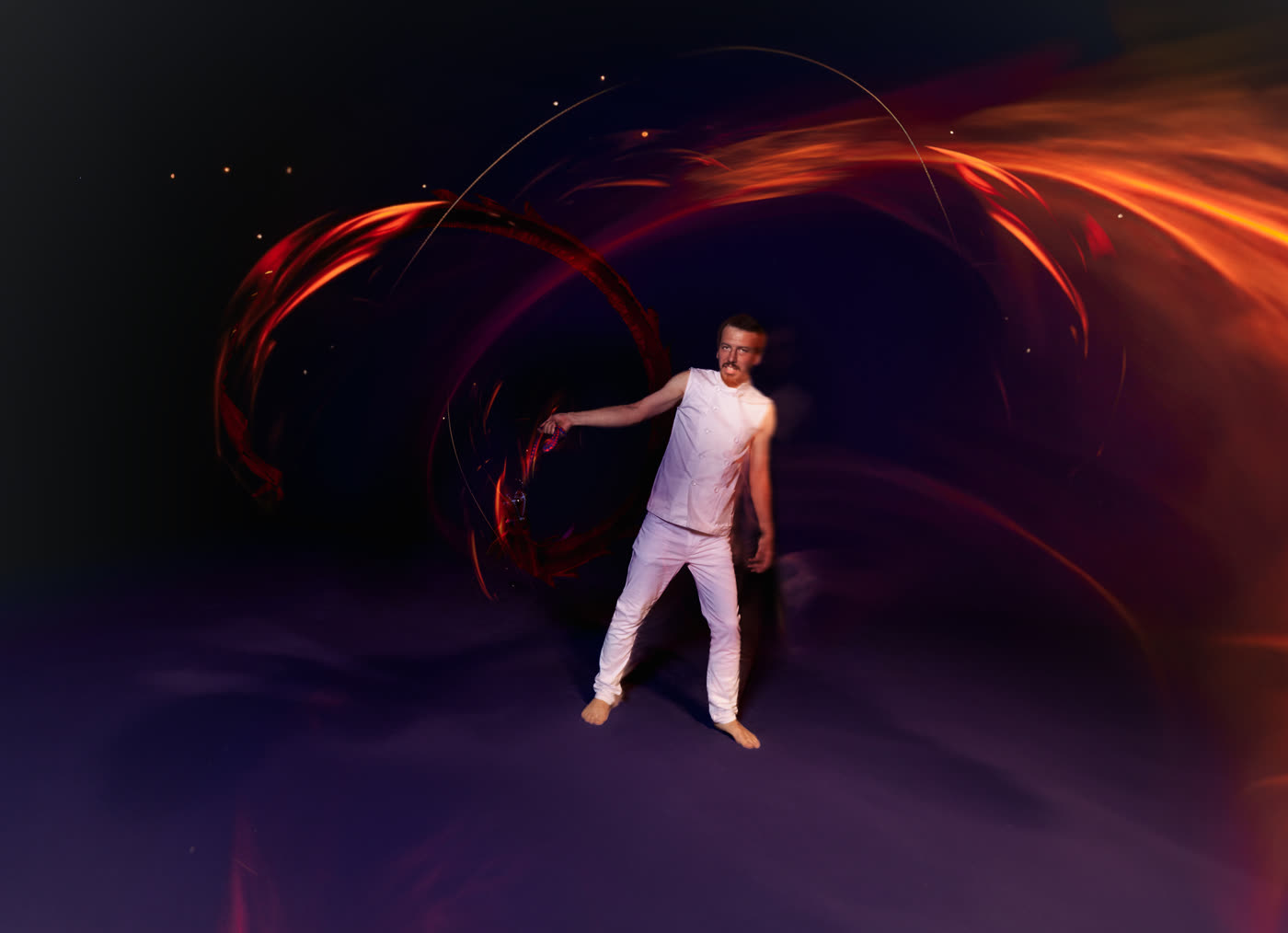Performer moving with LED props, multicoloured light trails